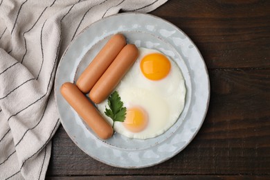 Photo of Delicious boiled sausages, fried eggs and parsley on wooden table, top view