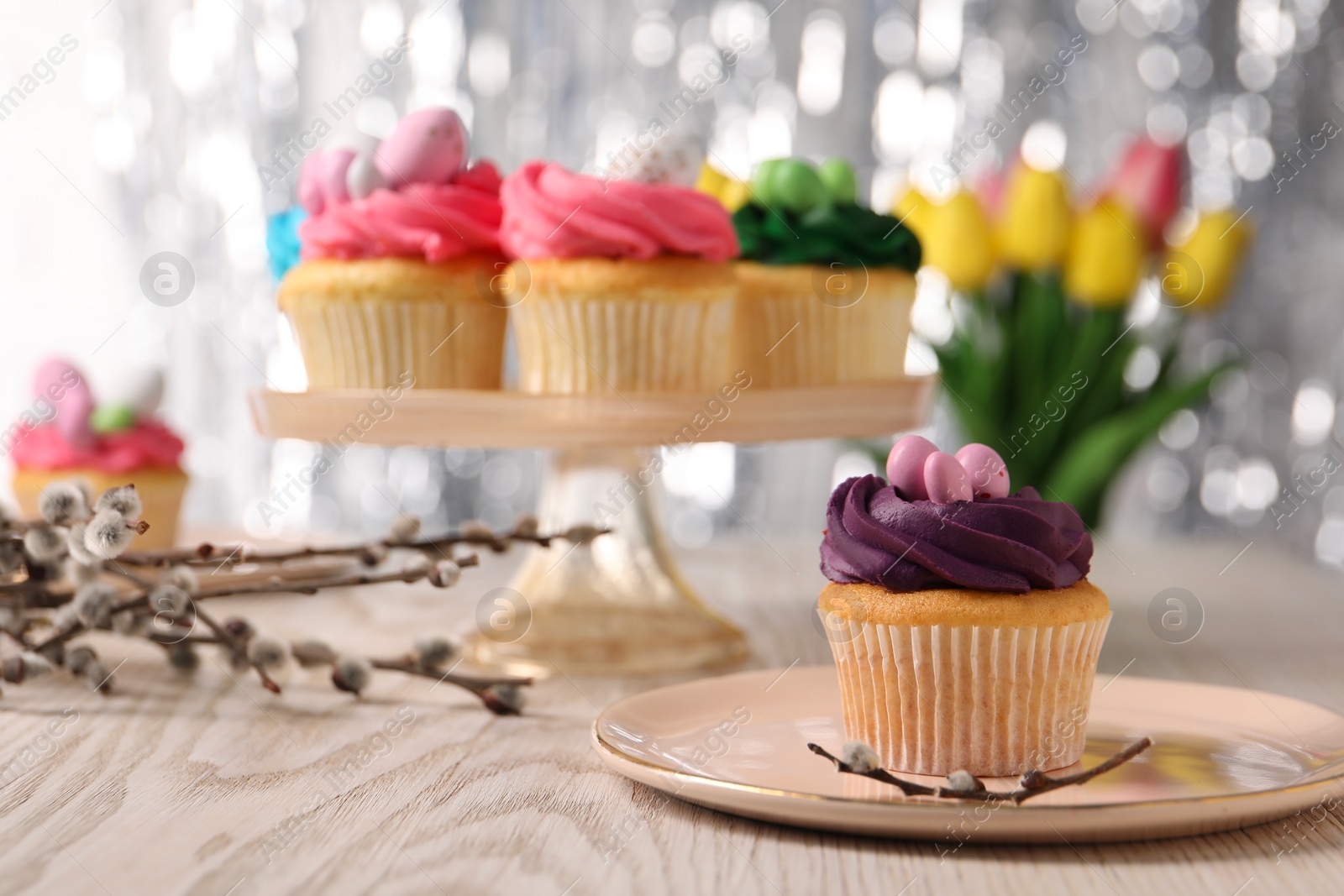 Photo of Tasty cupcakes with Easter decor on wooden table, selective focus