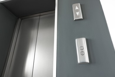 Elevator call buttons on grey wall near door