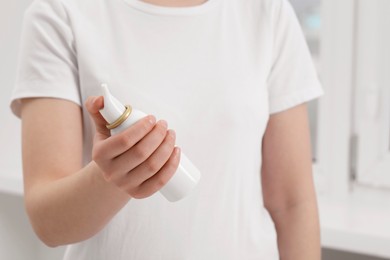 Woman holding bottle of nasal spray indoors, closeup