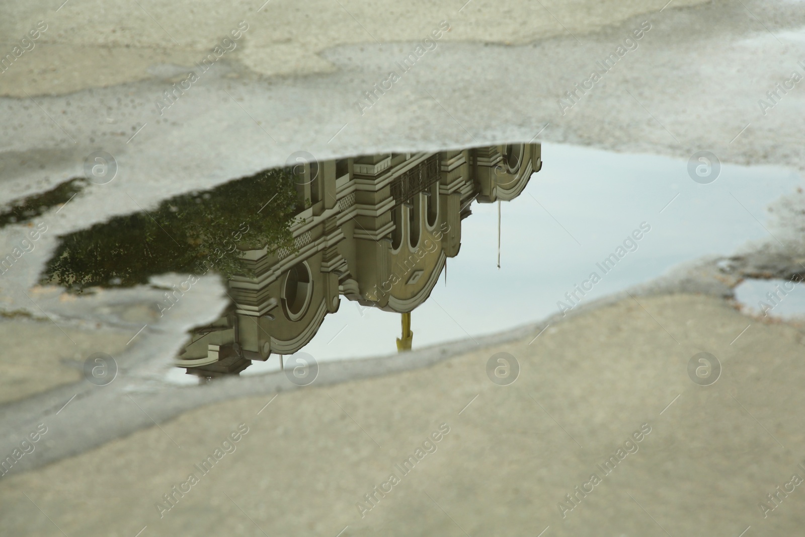 Photo of Reflection of beautiful building in puddle on asphalt