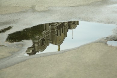 Photo of Reflection of beautiful building in puddle on asphalt