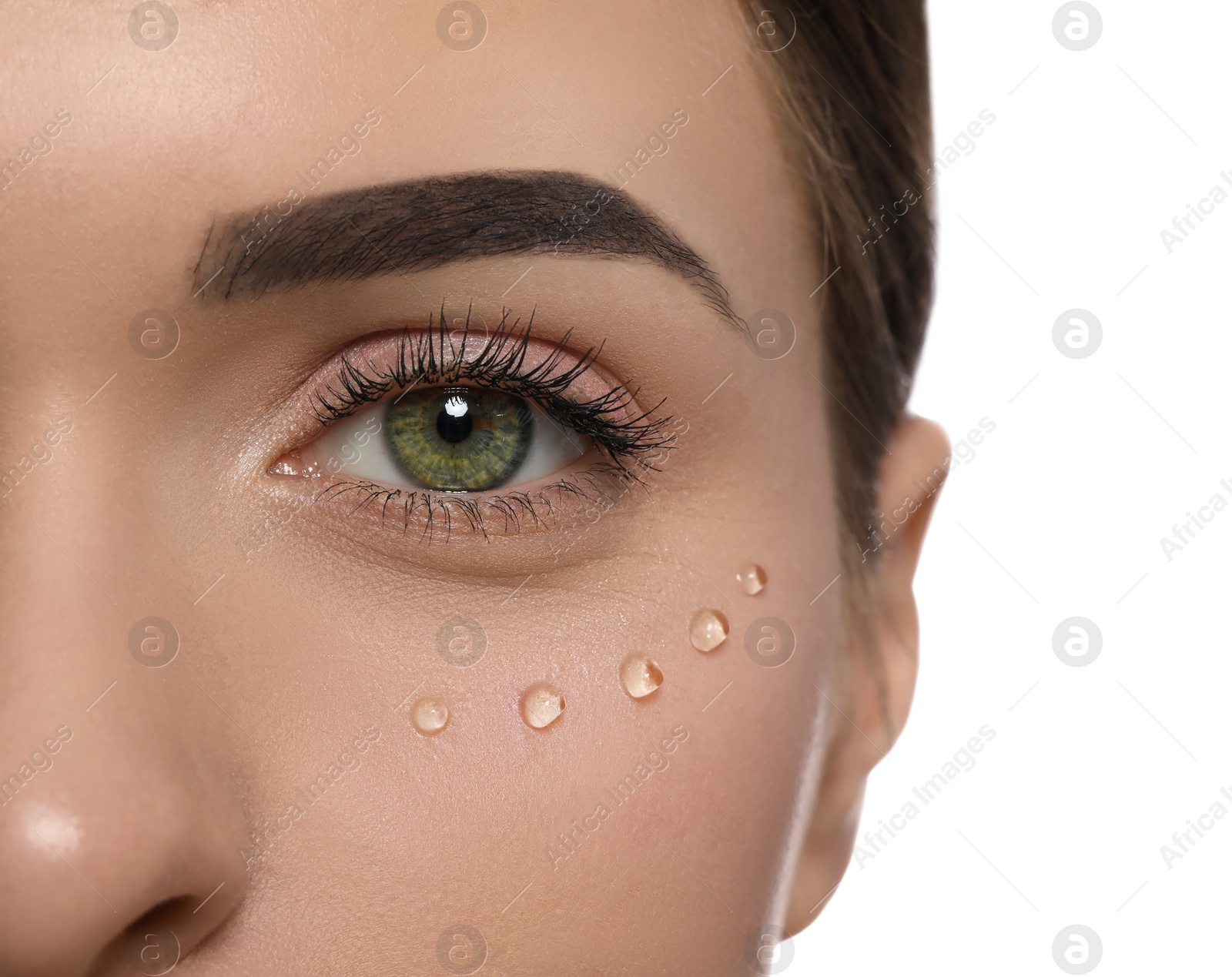 Photo of Young woman with cream around eye on white background, closeup