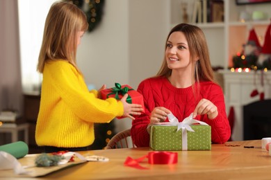 Photo of Christmas presents wrapping. Mother and her little daughter with gift boxes at table in room