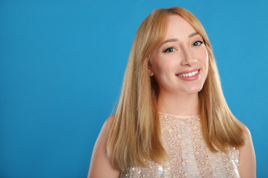 Portrait of beautiful young woman with blonde hair on blue background