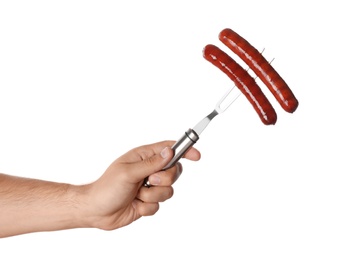 Man holding fork with grilled sausages on white background, closeup. Barbecue food