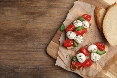 Delicious sandwiches with mozzarella, fresh tomatoes and basil on wooden table, top view. Space for text
