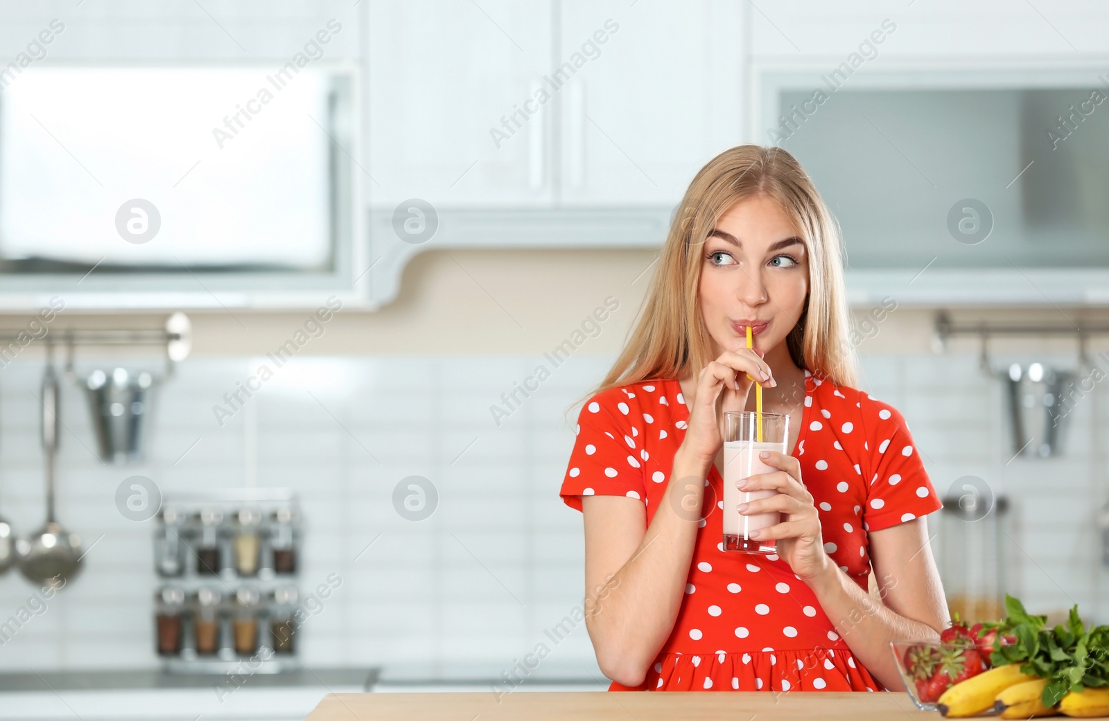 Photo of Young woman with glass of delicious milk shake in kitchen