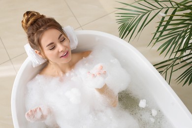 Photo of Beautiful woman enjoying bubble bath at home, above view