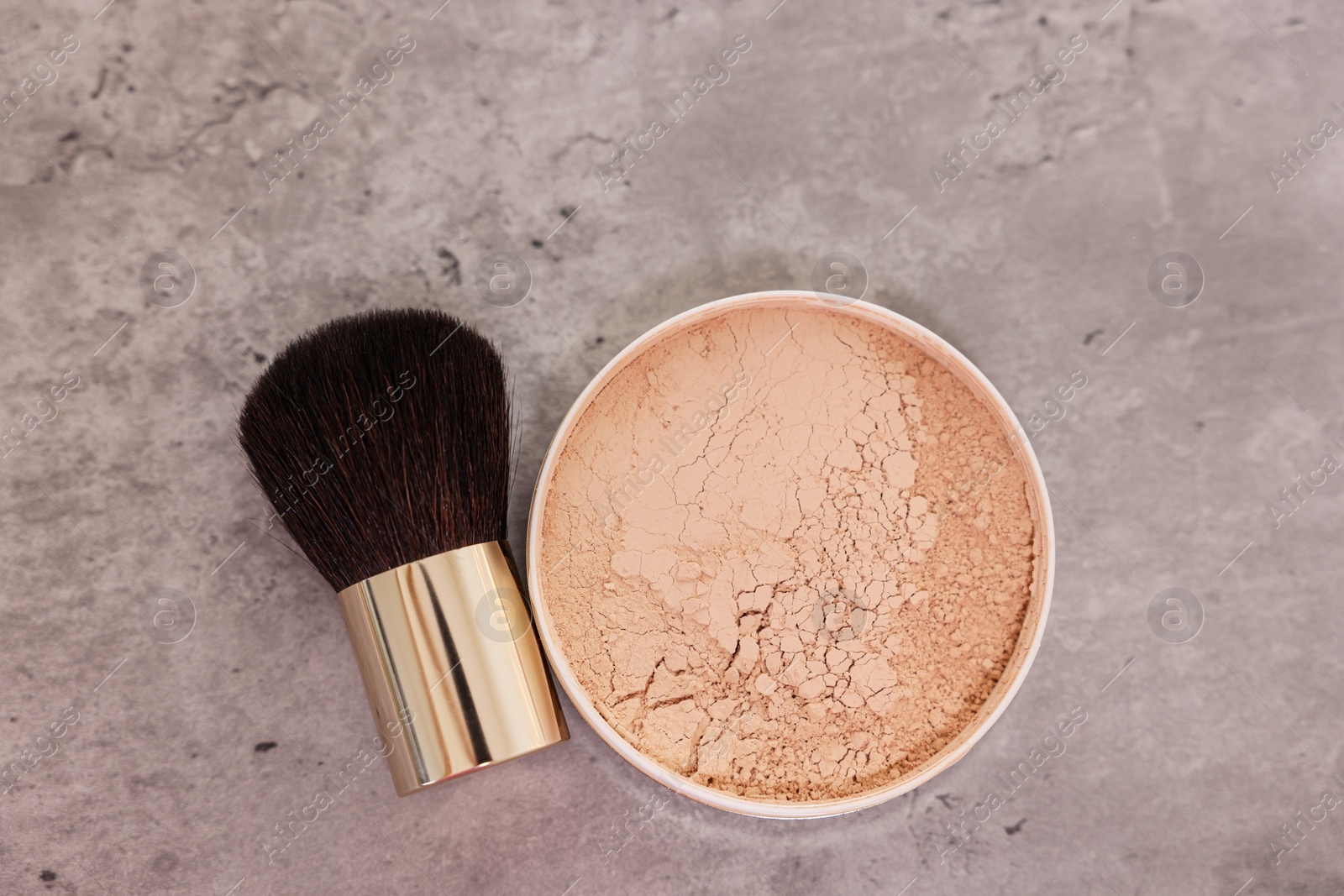 Photo of Face powder and brush on grey textured table, flat lay