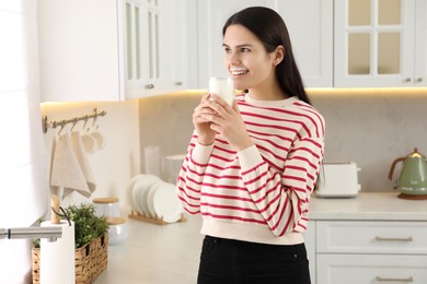 Cute woman with milk mustache drinking tasty dairy drink in kitchen. Space for text