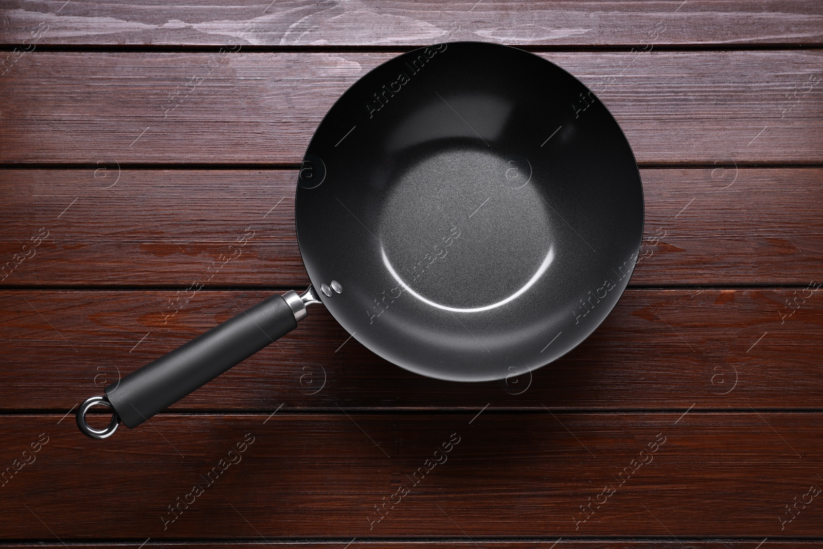 Photo of Empty iron wok on dark wooden table, top view. Chinese cookware