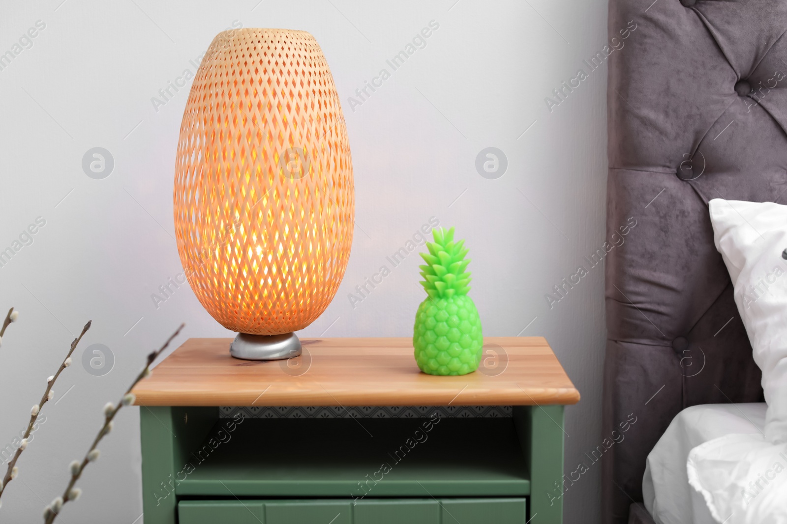 Photo of Pineapple shaped candle and lamp on bedside table in room