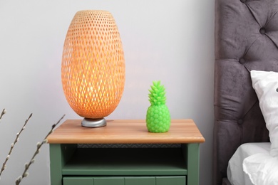 Pineapple shaped candle and lamp on bedside table in room