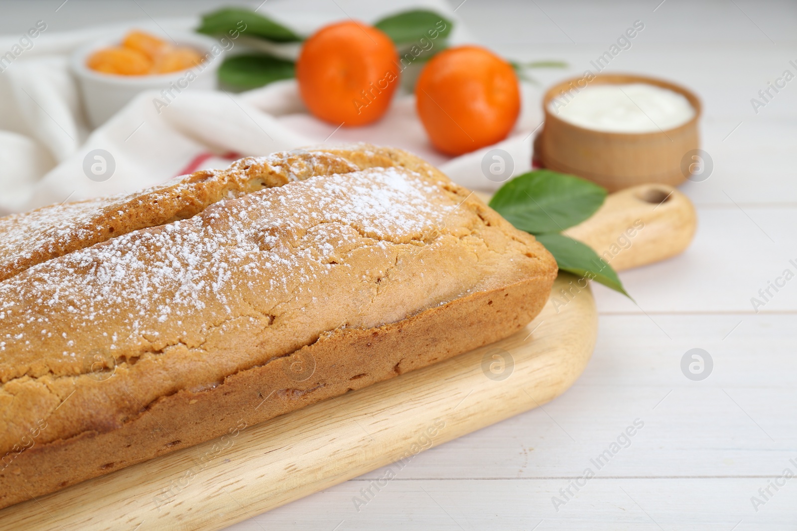 Photo of Delicious homemade yogurt cake with powdered sugar on white wooden table, closeup