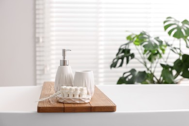 Set of different bath accessories and soap on tub in bathroom, space for text