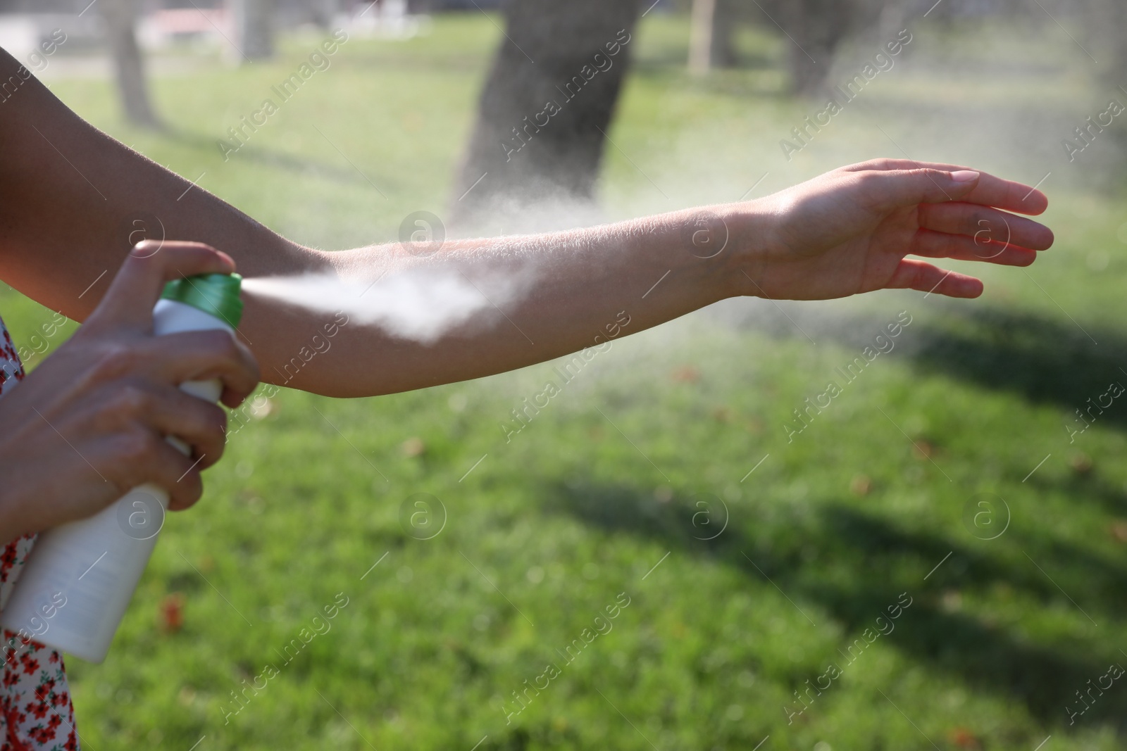 Photo of Woman applying insect repellent onto hand in park, closeup