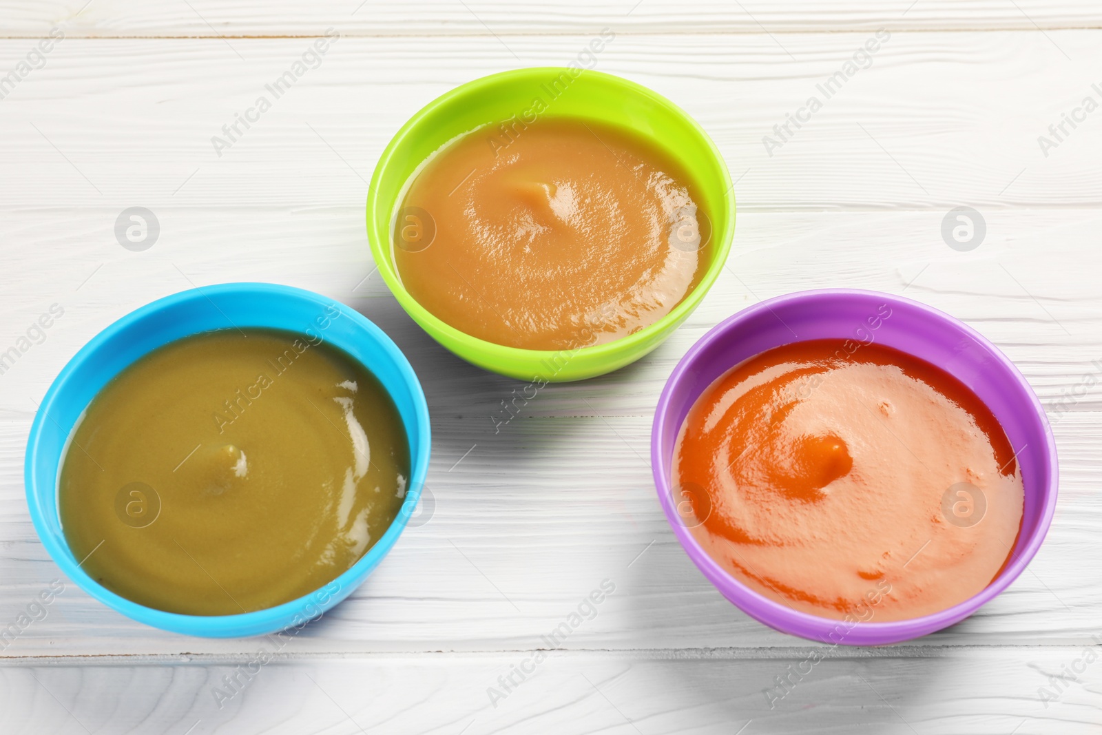 Photo of Baby food. Different purees in bowls on white wooden table