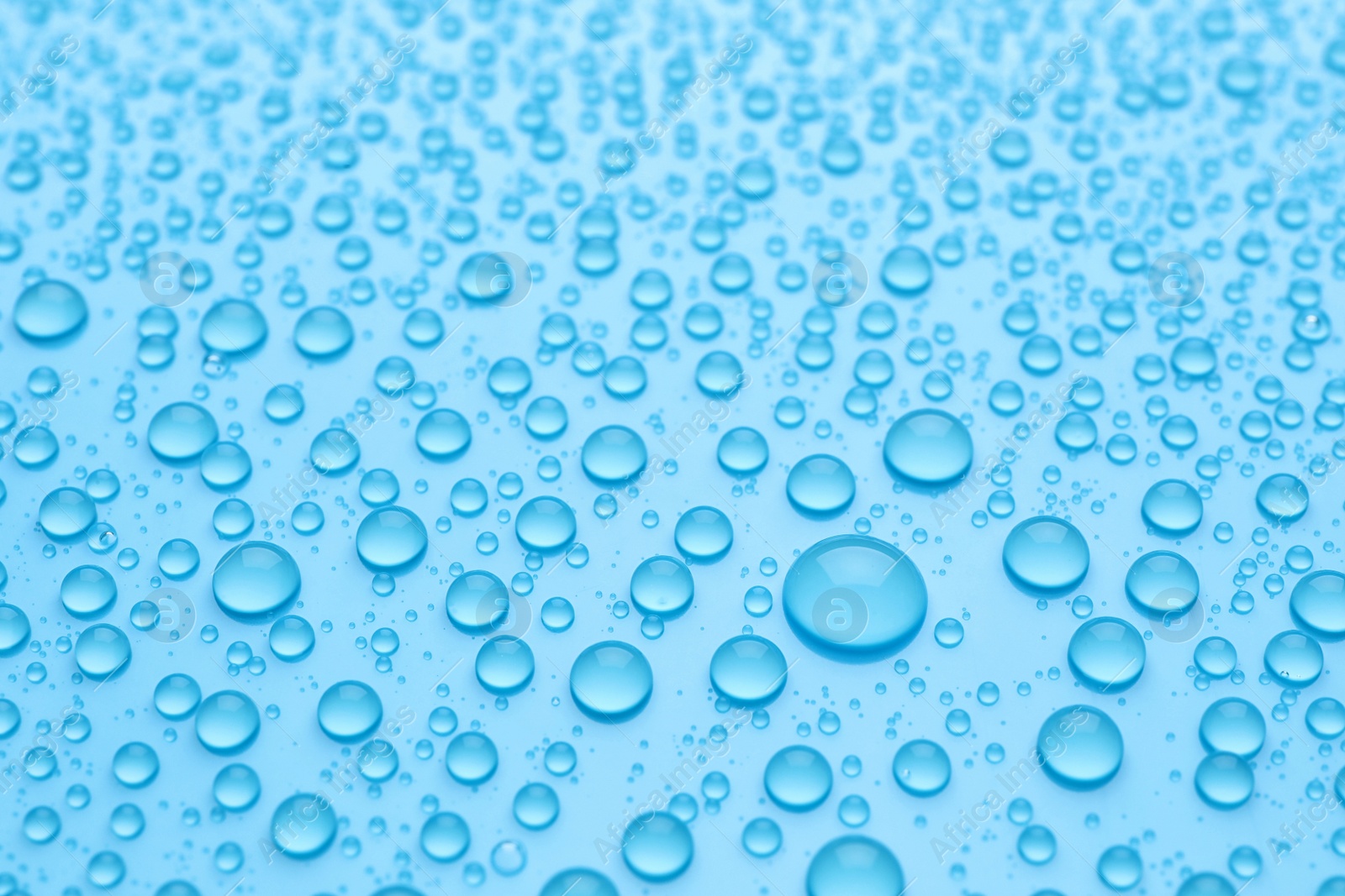 Photo of Water drops on light blue background, closeup view