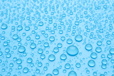 Water drops on light blue background, closeup view