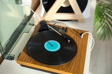 Stylish turntable with vinyl disc and headphones on white table at home, closeup