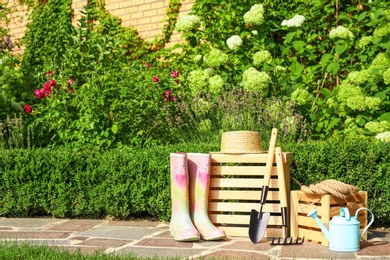 Photo of Wooden crates and gardening tools on stone path at backyard