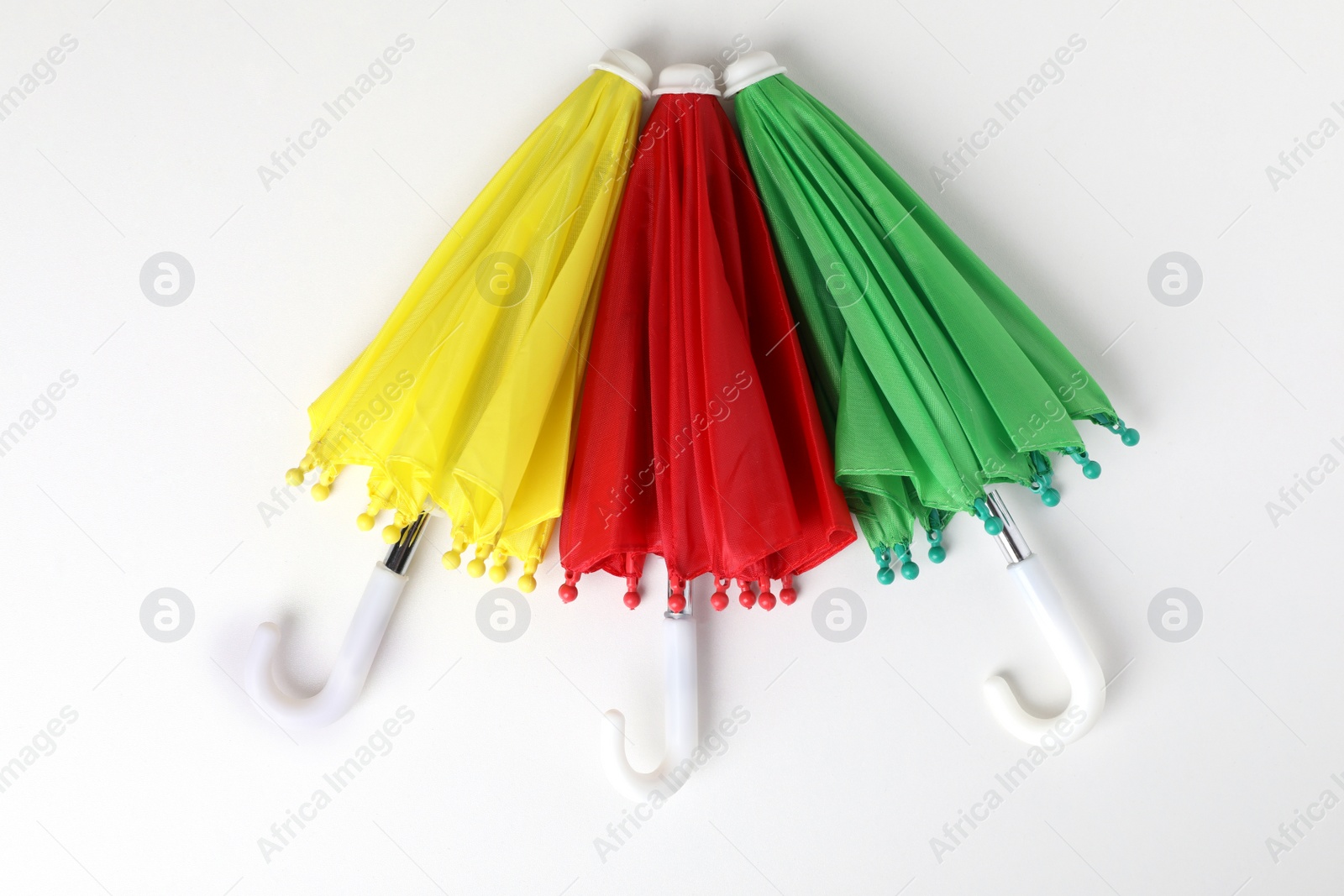 Photo of Small color umbrellas on white background, top view