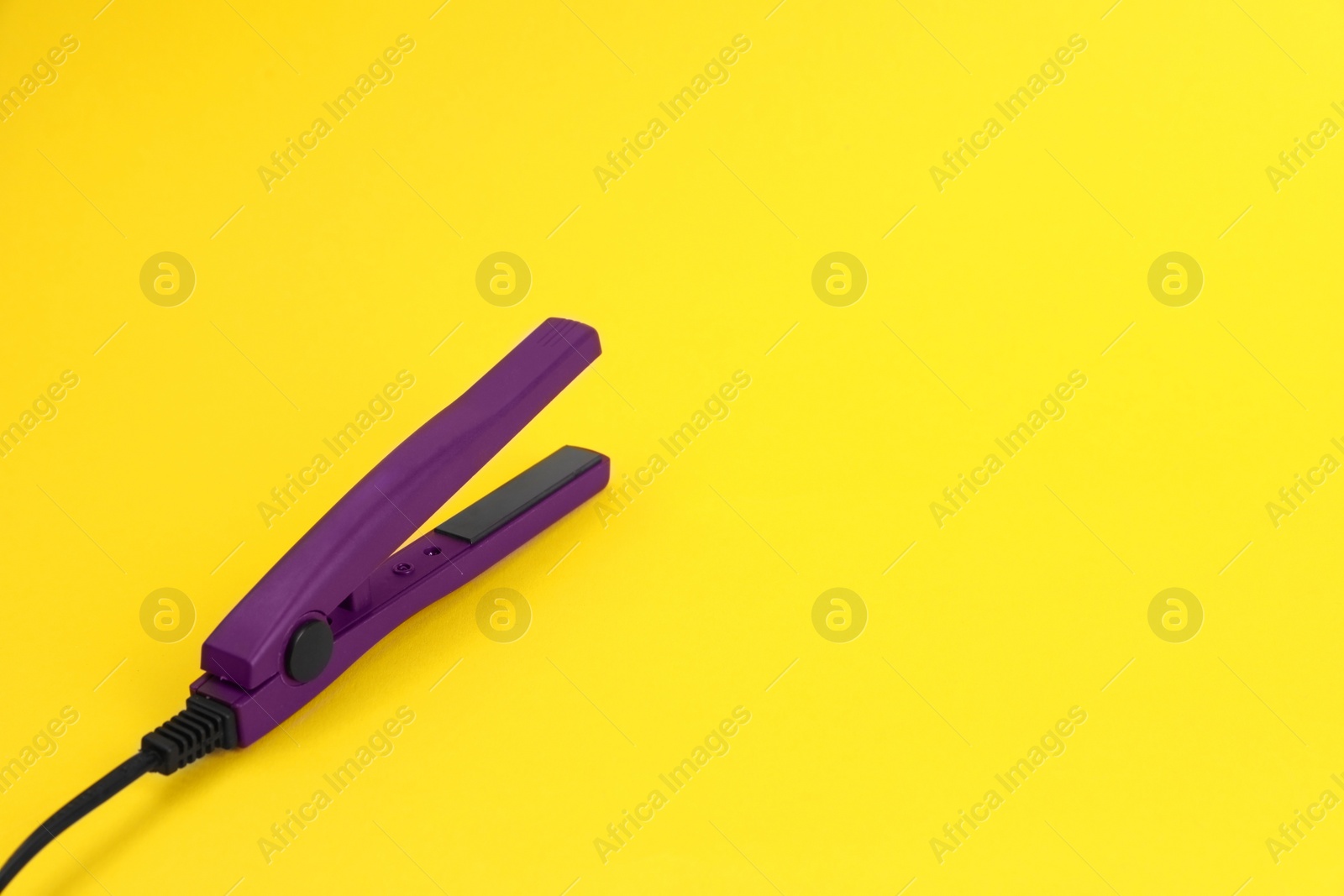 Photo of Modern hair iron for straightening on color background. Space for text