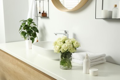 Photo of Beautiful roses and bath accessories near sink in bathroom