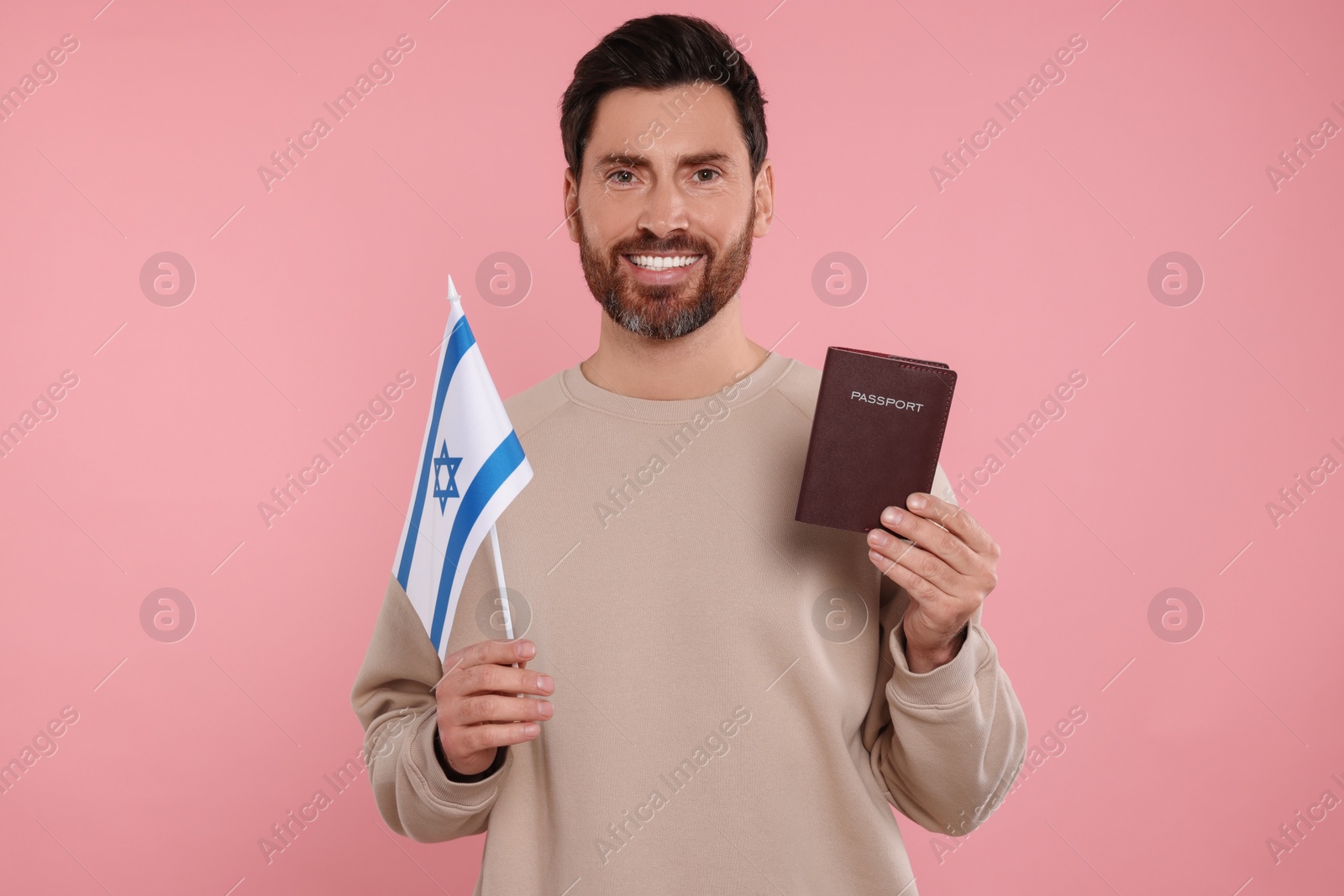 Photo of Immigration. Happy man with passport and flag of Israel on pink background