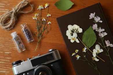 Photo of Flat lay composition with beautiful dried flowers, vintage camera and book on wooden table