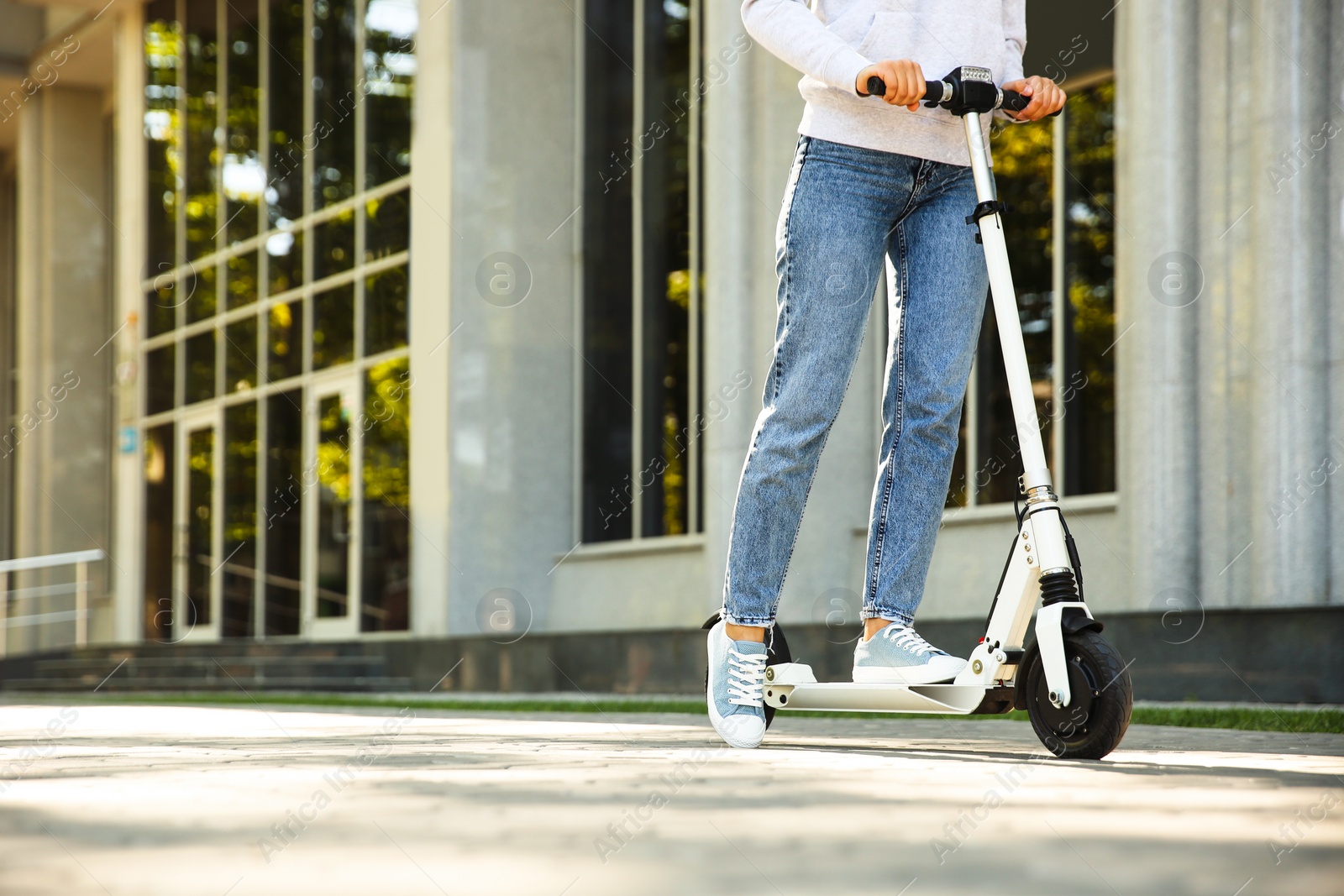 Photo of Woman riding electric kick scooter outdoors. Space for text