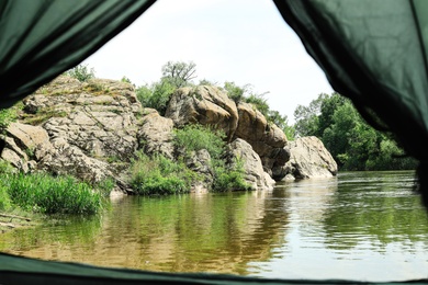 Photo of Calm river with rocky bank, view from camping tent