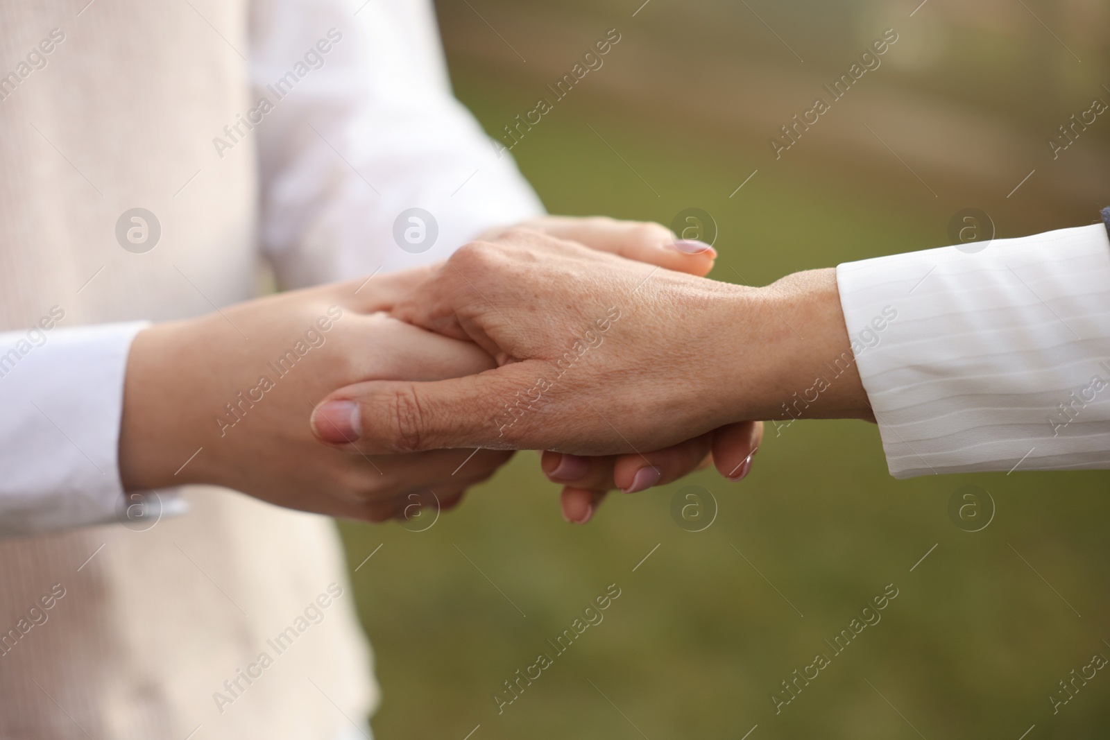 Photo of Trust and support. Women joining hands outdoors, closeup