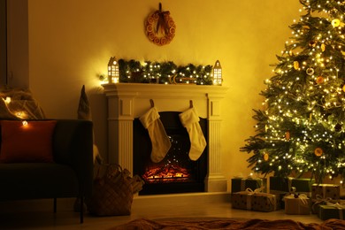 Stylish fireplace near decorated Christmas tree and accessories in cosy room