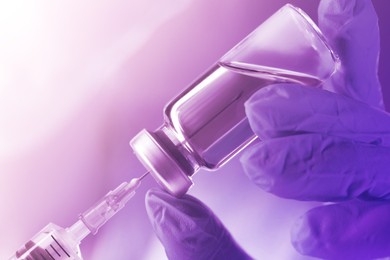 Image of Doctor filling syringe with medication from vial, closeup. Color toned