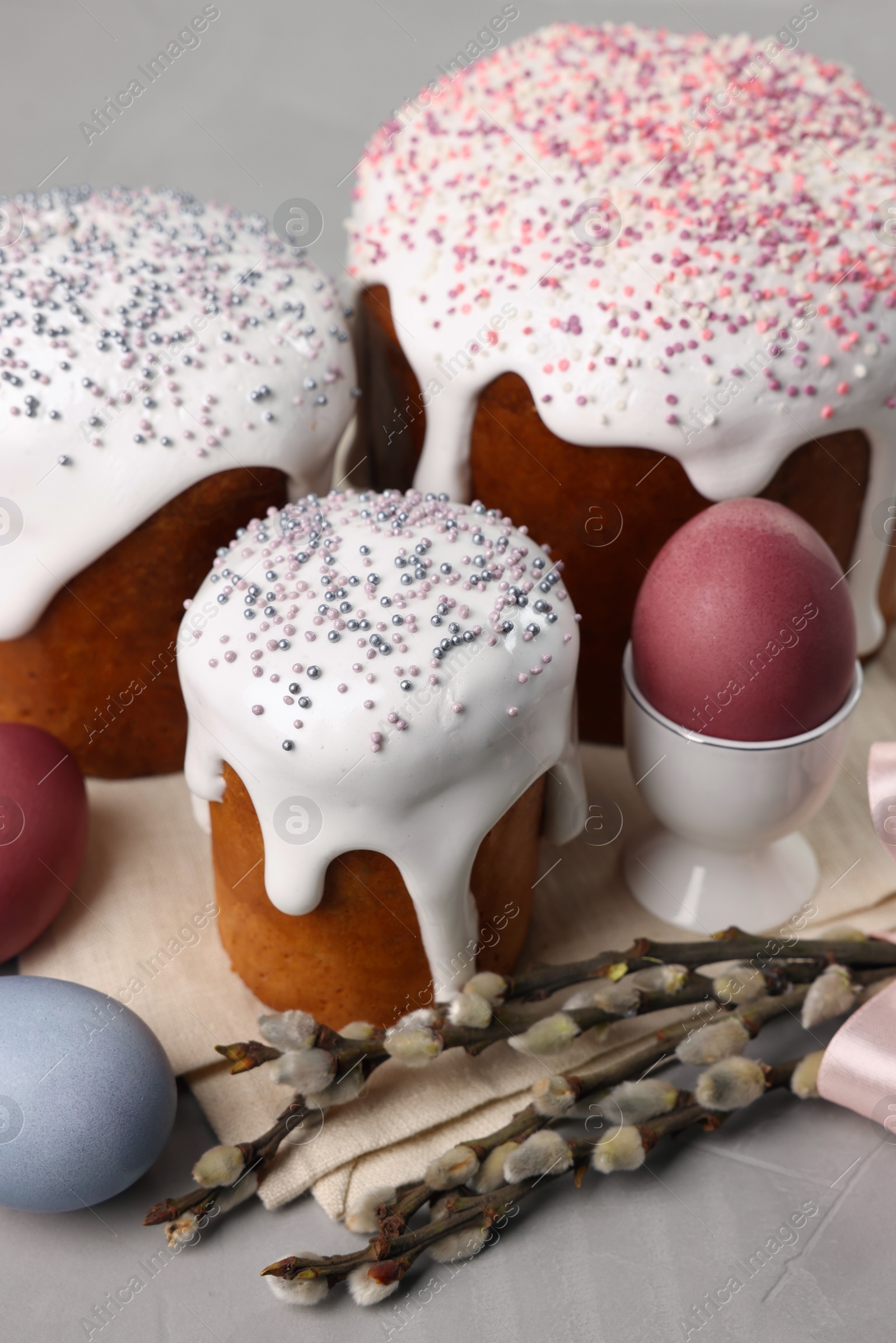 Photo of Tasty Easter cakes, decorated eggs and willow branches on grey table