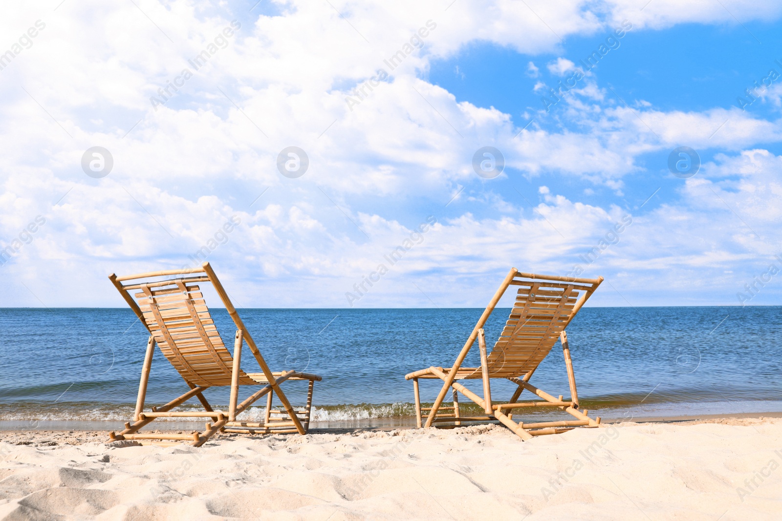 Photo of Sandy beach with empty wooden sunbeds on sunny day