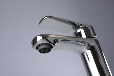 Photo of Single handle water tap on grey background, closeup