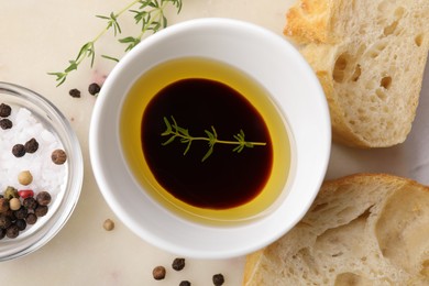 Photo of Bowl of organic balsamic vinegar with oil and spices served with bread slices on beige table, flat lay