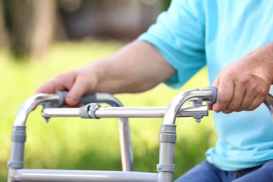 Photo of Elderly man with walking frame outdoors, closeup. Medical help