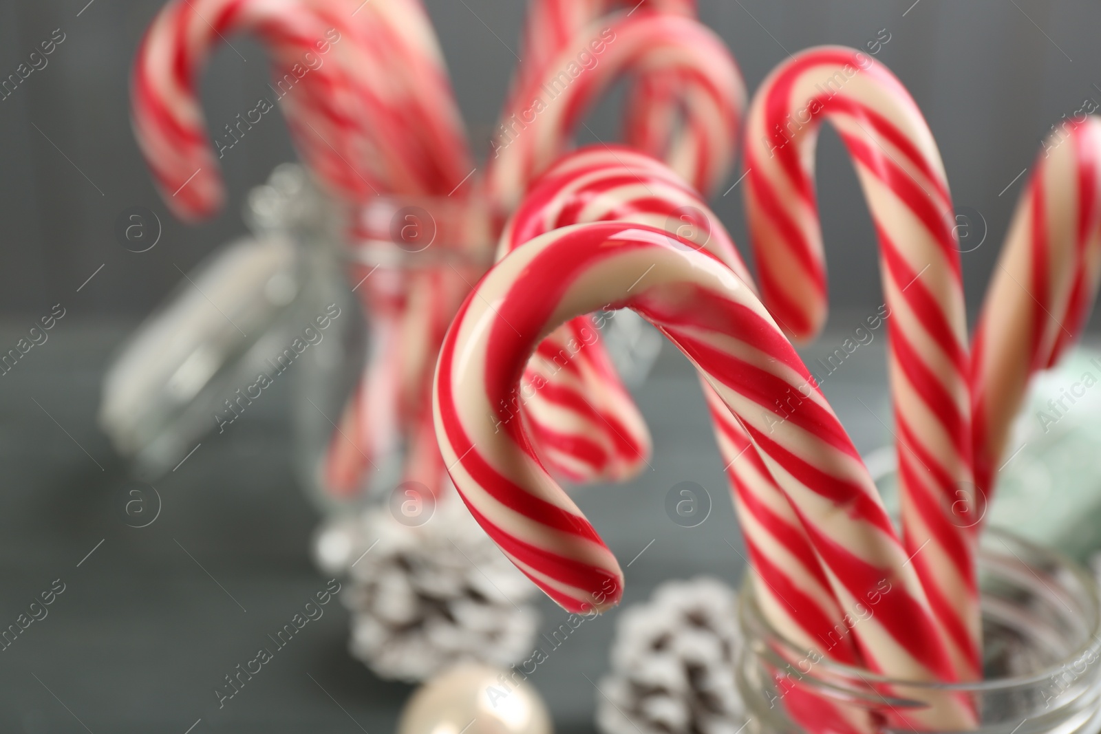 Photo of Many sweet candy canes in glass on table, closeup. Traditional Christmas treat