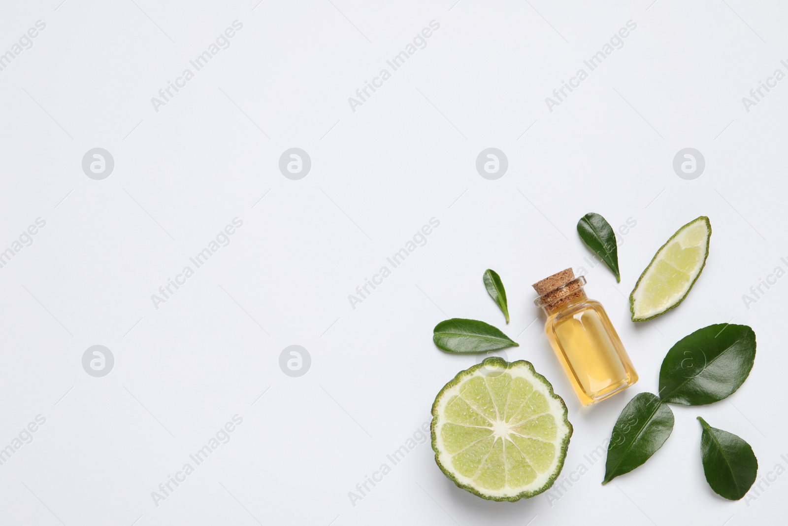 Photo of Glass bottle of bergamot essential oil and fresh fruit on white background, flat lay. Space for text