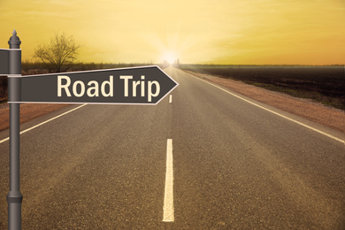 Image of Plaque with inscription road trip on asphalt highway at sunset 