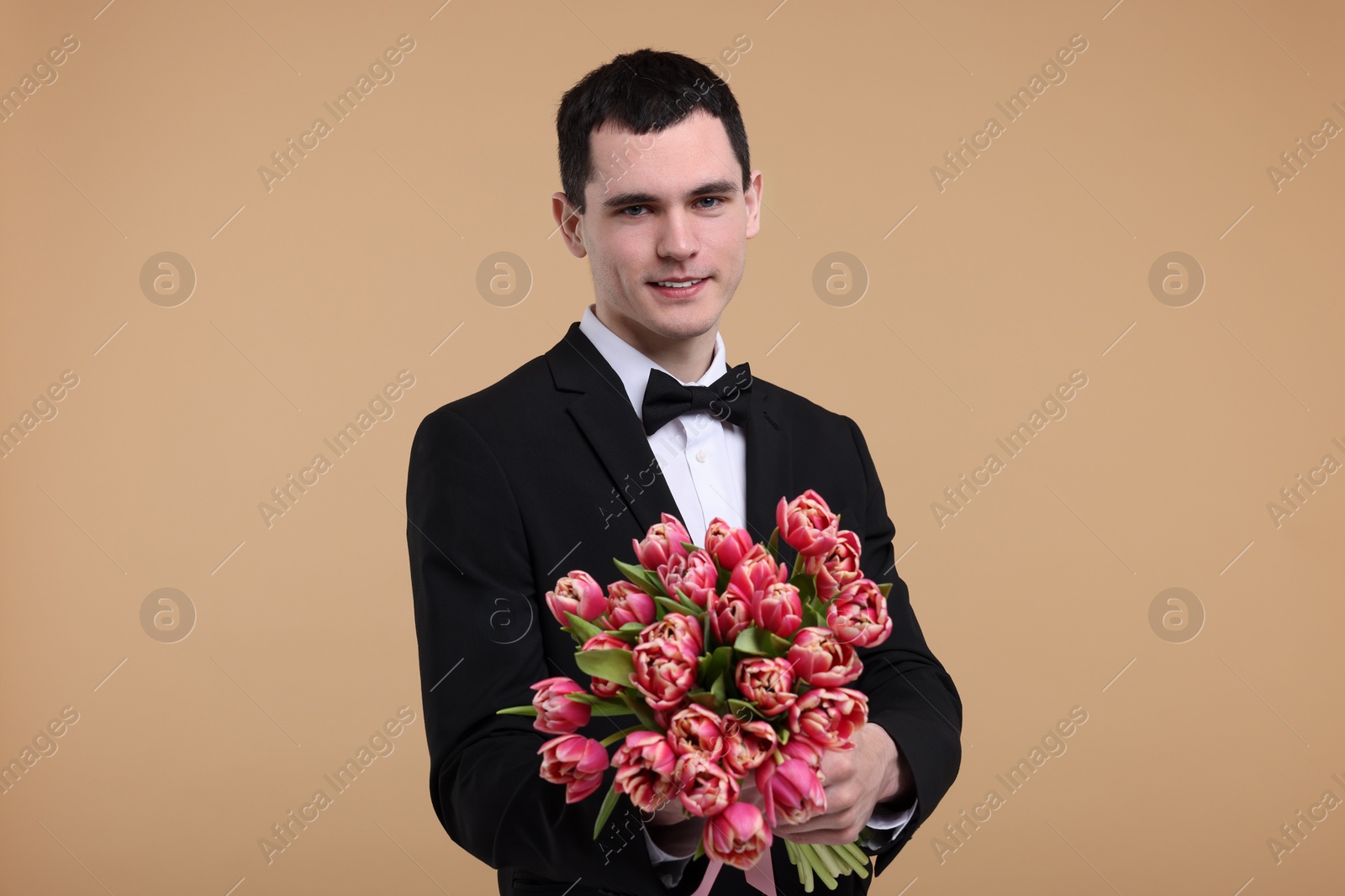 Photo of Happy young man with beautiful bouquet on beige background