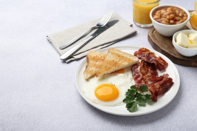 Photo of Delicious breakfast with sunny side up egg served on light table. Space for text