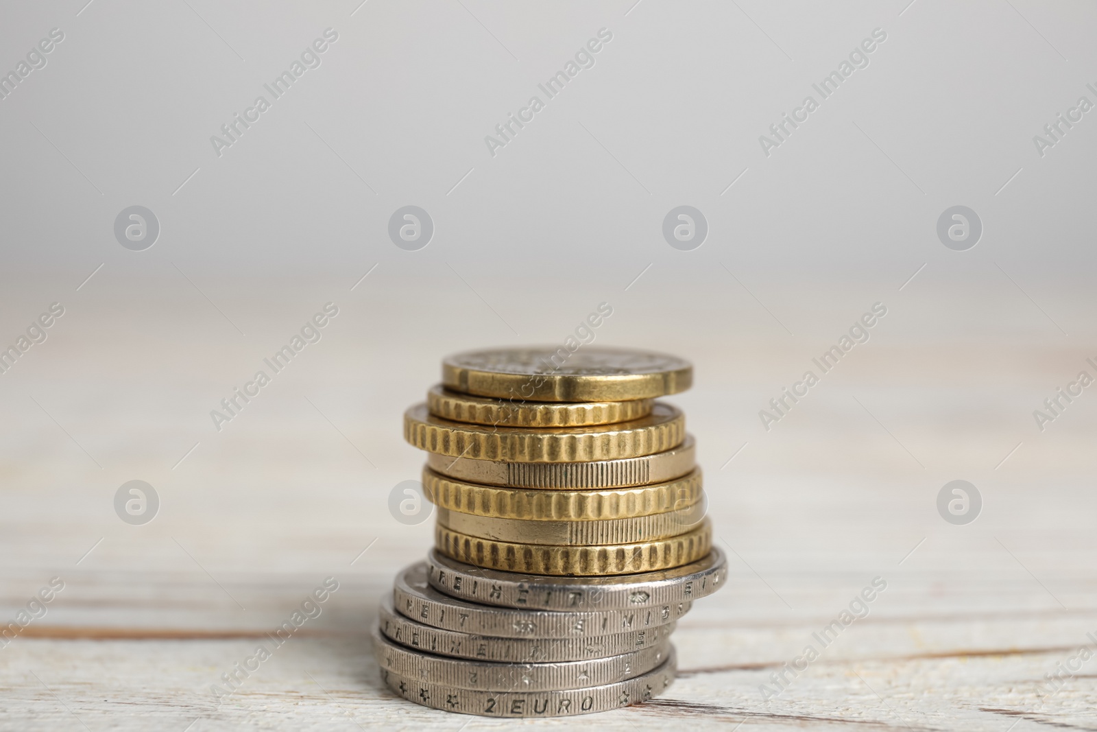 Photo of Many Euro coins stacked on white wooden table, closeup