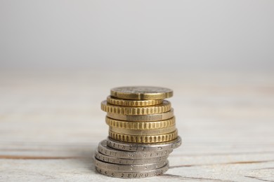 Photo of Many Euro coins stacked on white wooden table, closeup