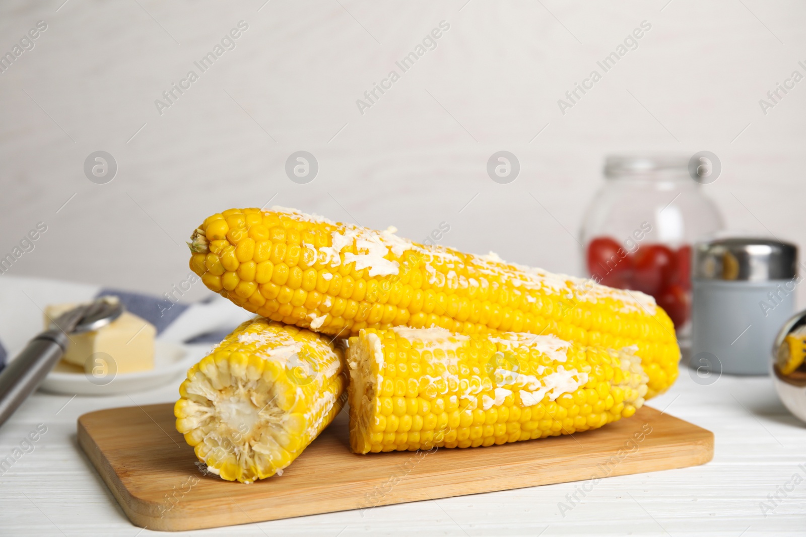 Photo of Fresh corn cobs with butter on white wooden table, closeup
