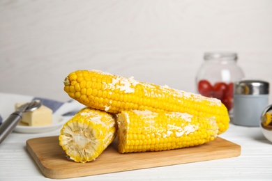 Fresh corn cobs with butter on white wooden table, closeup